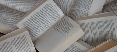 Open books stacked randomly atop eachother.