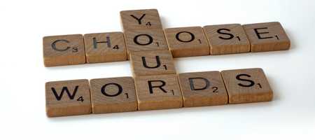 Scrabble pieces spelling out "Choose your words".