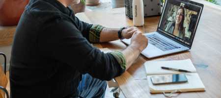 A man is on his laptop, talking to a tutor online.