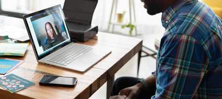 A man talking to a woman through an app on his laptop.